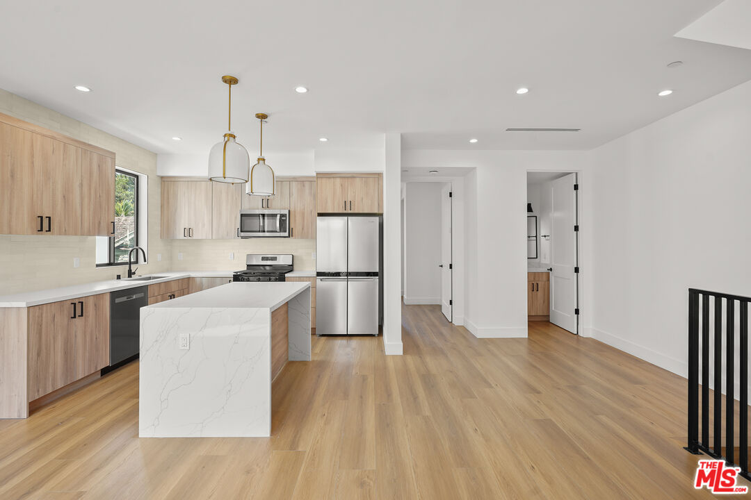 a kitchen with kitchen island wooden floors appliances and cabinets