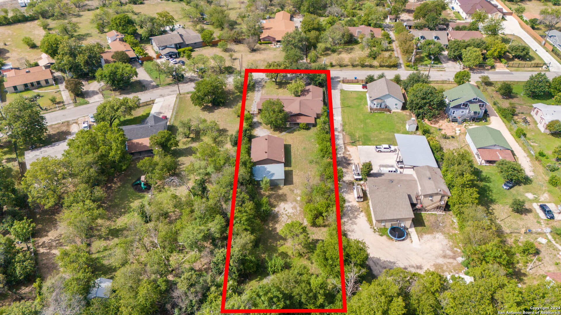 an aerial view of residential houses with outdoor space and trees