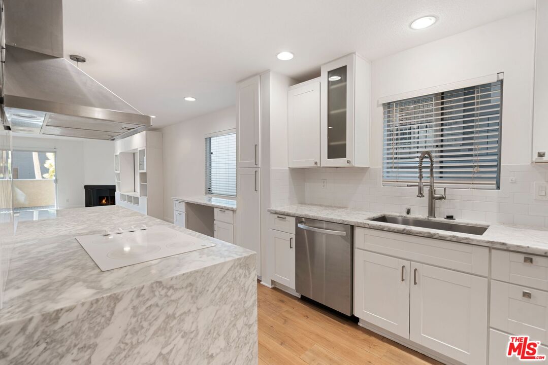 a large white kitchen with a sink large white cabinets and stainless steel appliances