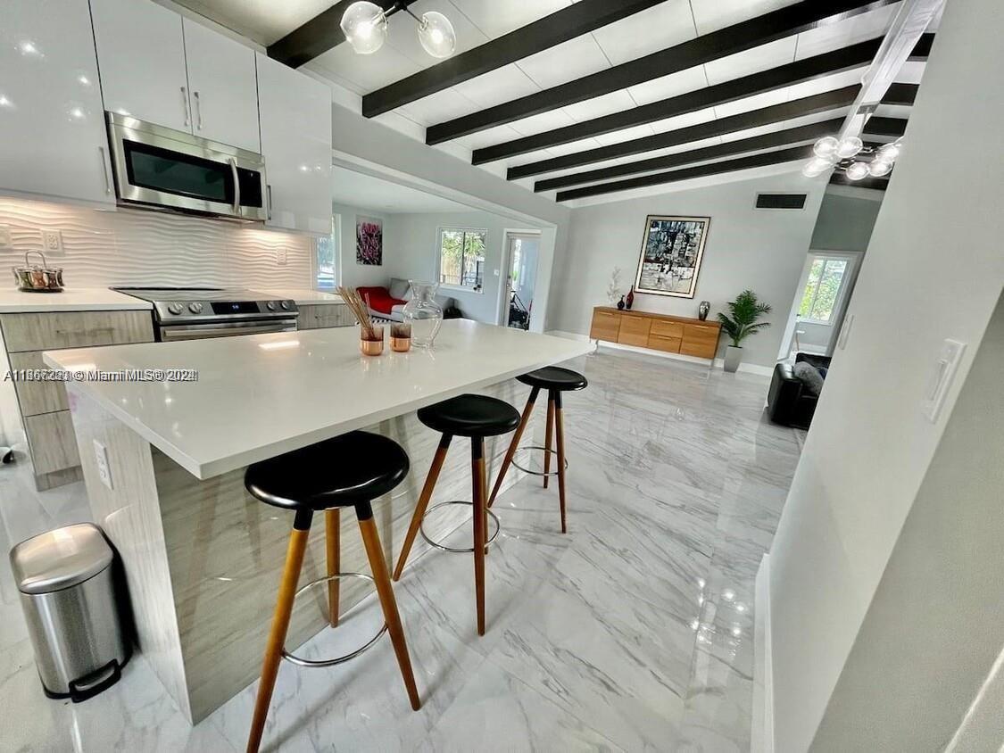 a kitchen with stainless steel appliances kitchen island a table chairs in it and wooden floors