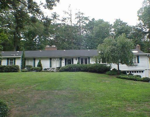 a front view of a house with a garden and trees