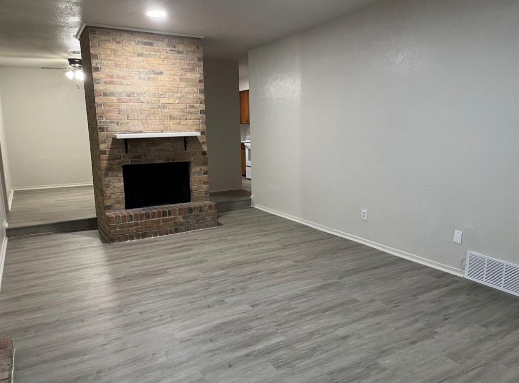 a view of empty room with wooden floor and fireplace