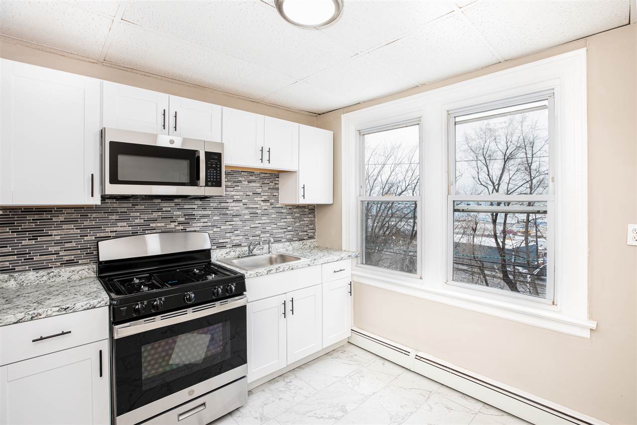 a kitchen with granite countertop a stove a microwave a sink and cabinets