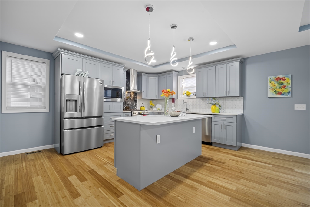 a kitchen with stainless steel appliances granite countertop a refrigerator a stove top oven a sink dishwasher and a refrigerator with wooden floor