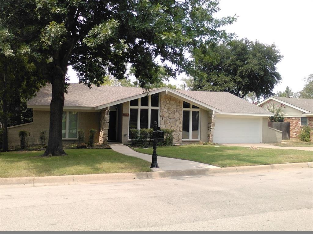 a view of a house with a yard and large tree