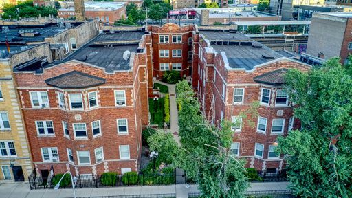 a front view of a residential apartment building with a yard and potted plants