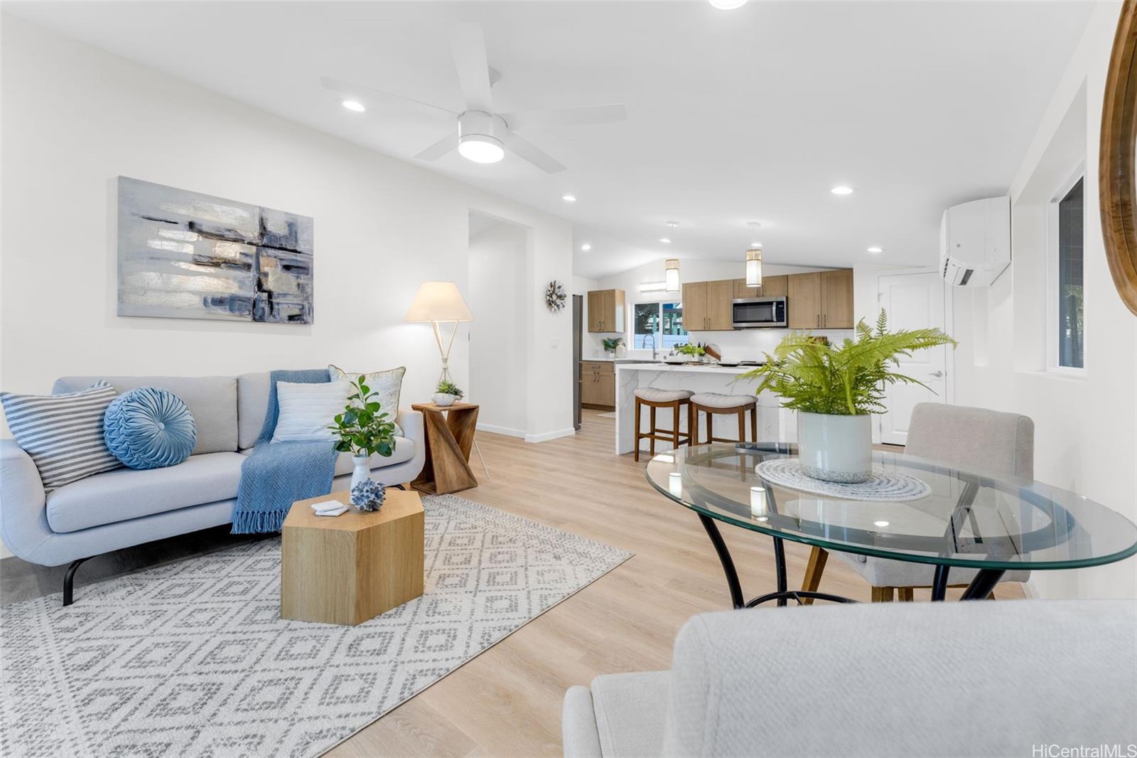 a living room with furniture potted plant and kitchen view