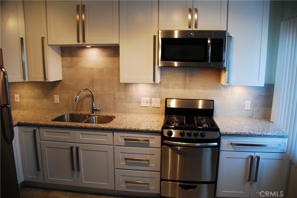 a kitchen with stainless steel appliances granite countertop a stove a sink and a microwave