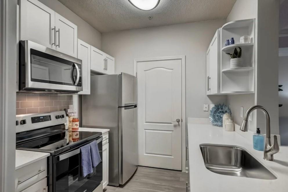 a kitchen with stainless steel appliances a refrigerator sink and microwave