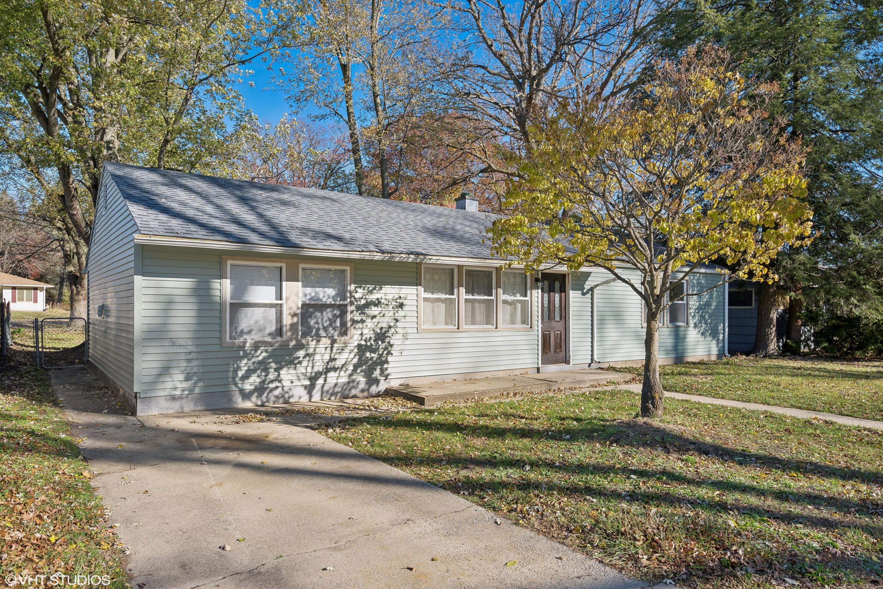 a front view of a house with a garden and trees