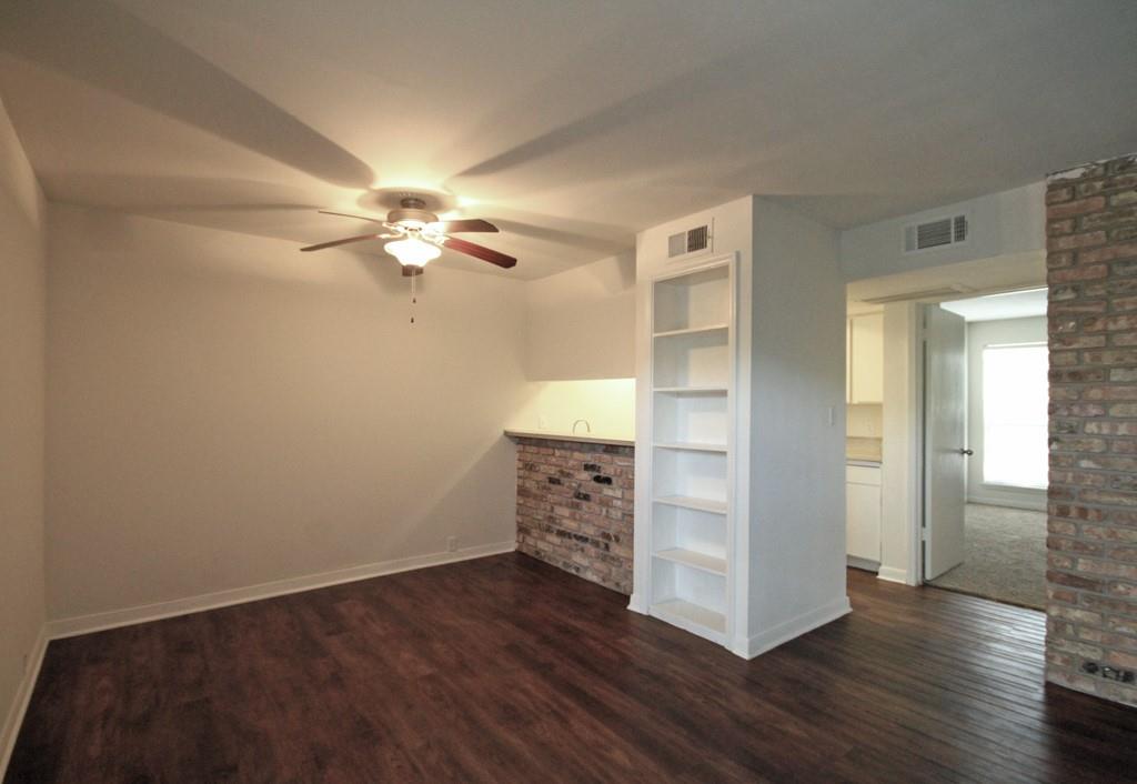 an empty room with wooden floor closet and windows