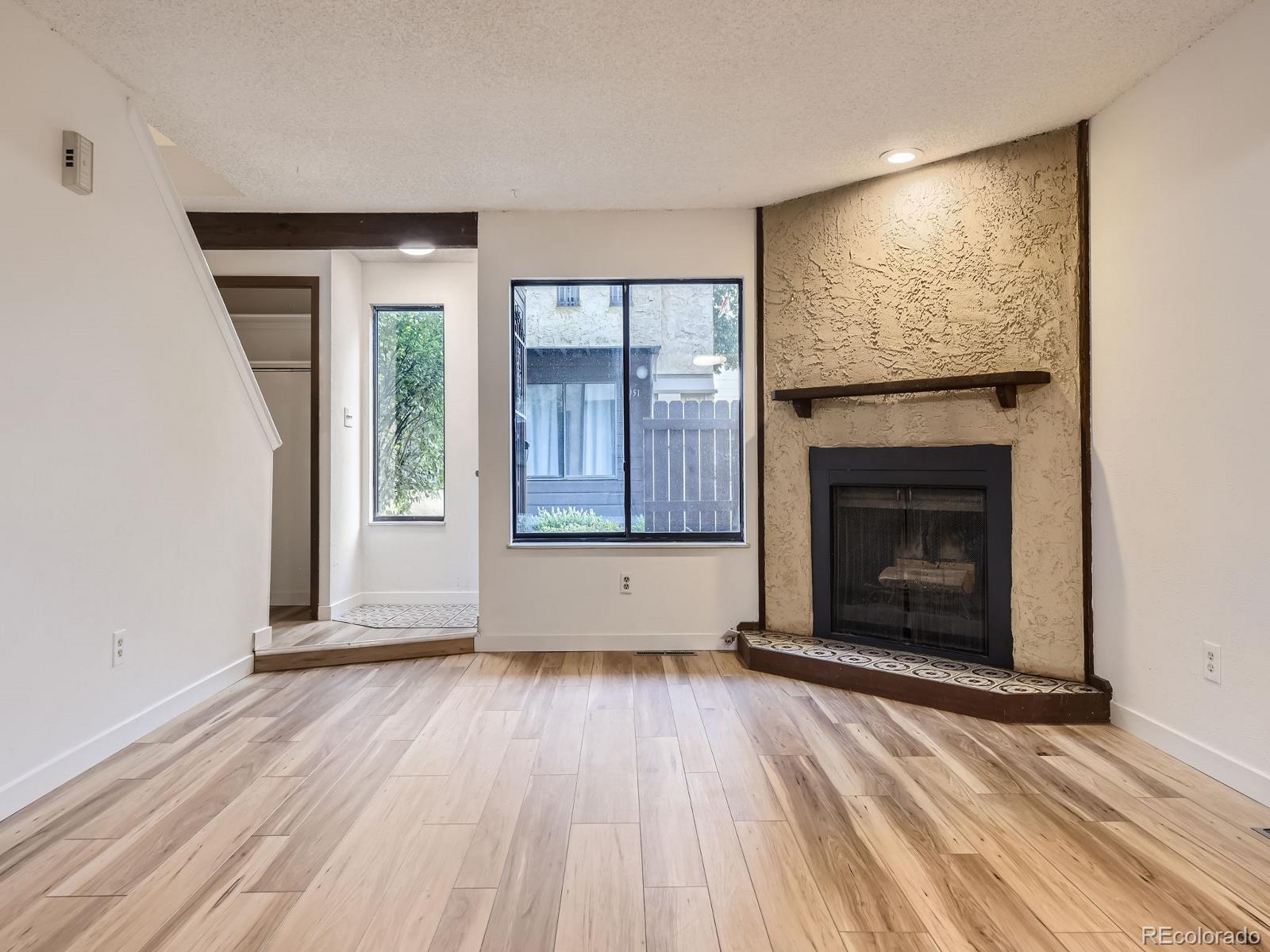 an empty room with wooden floor fireplace and windows