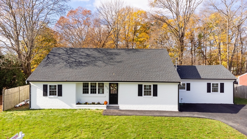 a front view of a house with a yard and trees