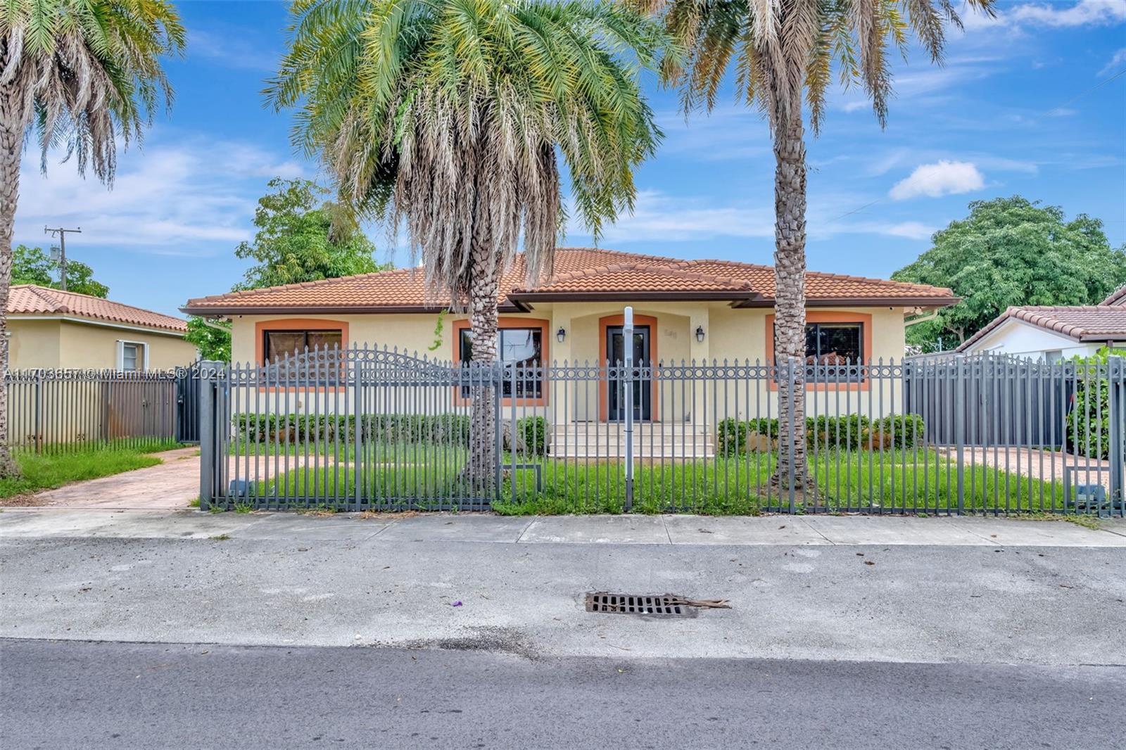 a front view of a house with a garden and palm trees