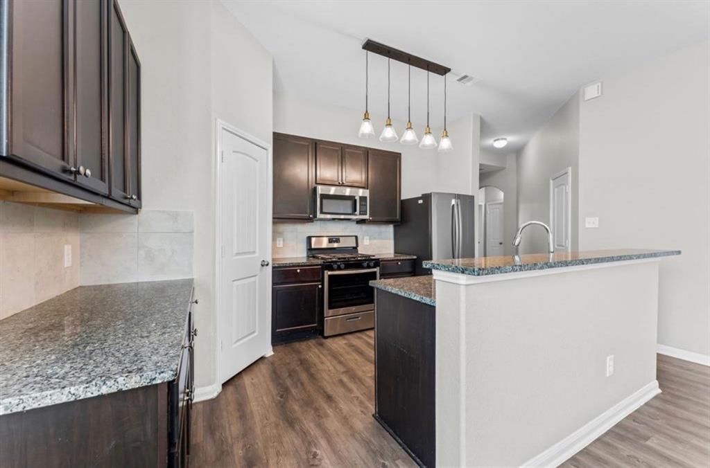 a kitchen with kitchen island granite countertop stainless steel appliances and wooden cabinets