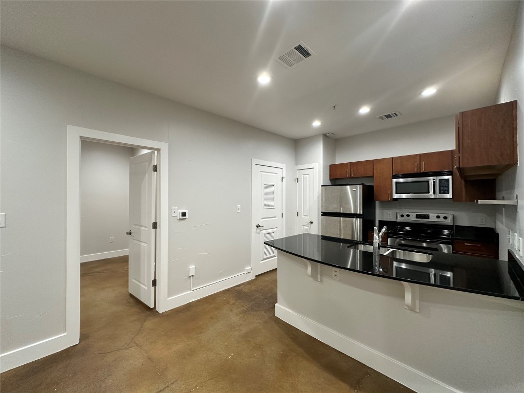 a large kitchen with stainless steel appliances granite countertop a sink and a refrigerator