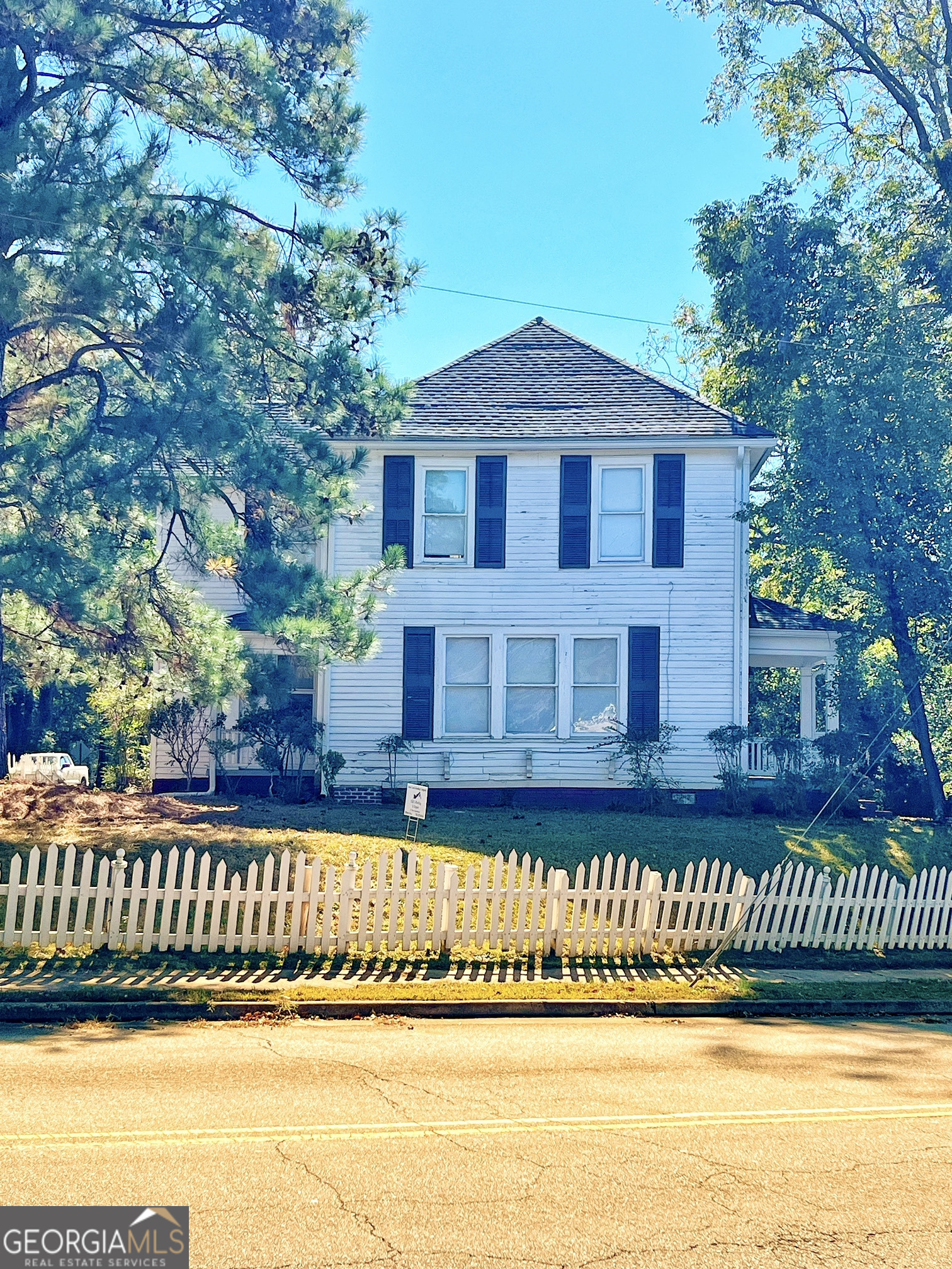 a view of a brick house next to a yard with large trees