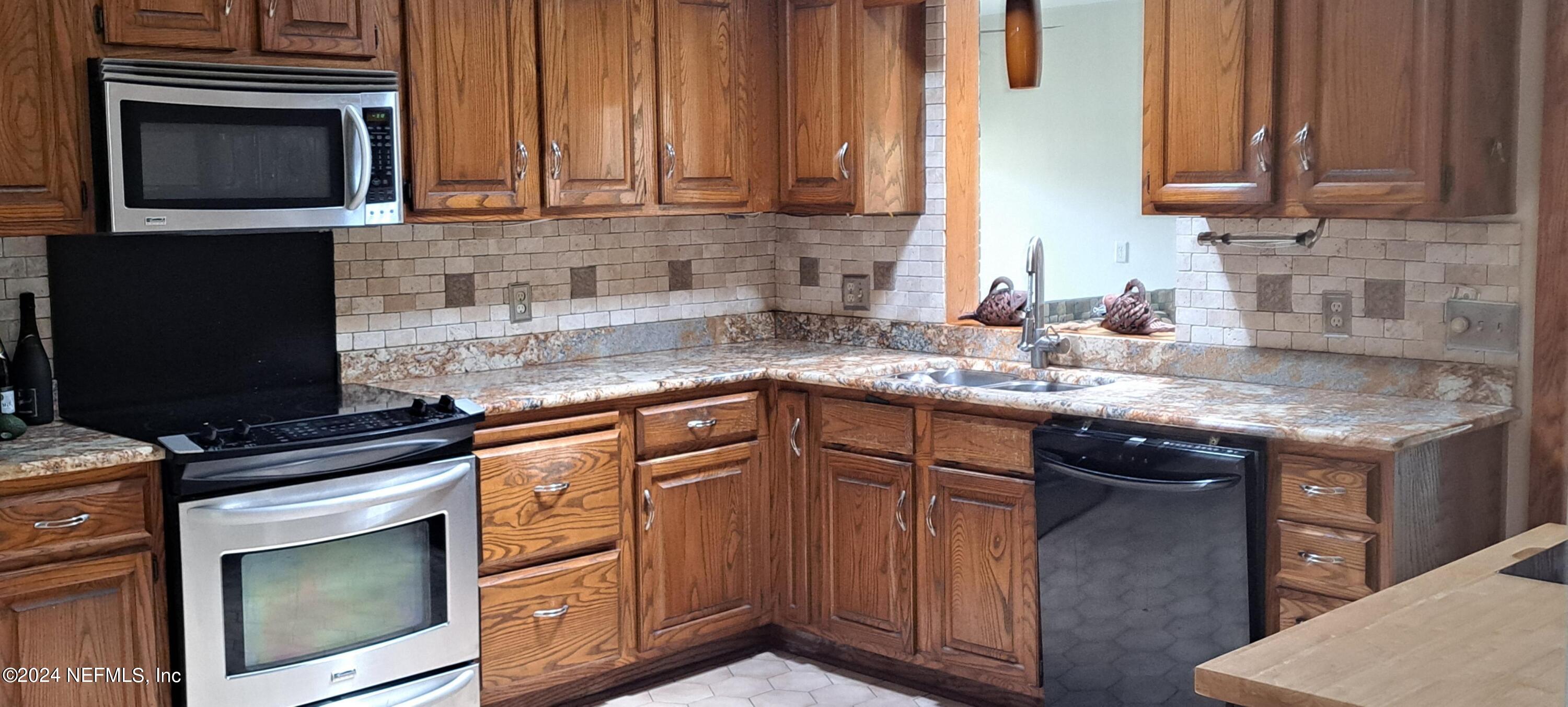 a kitchen with granite countertop a sink stove and microwave