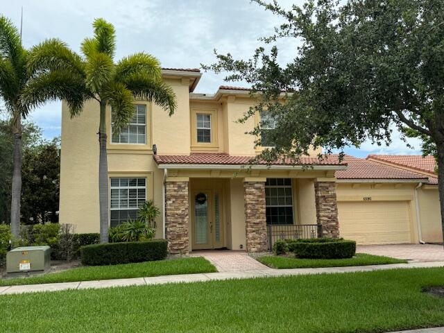 front view of a house with a yard and palm trees