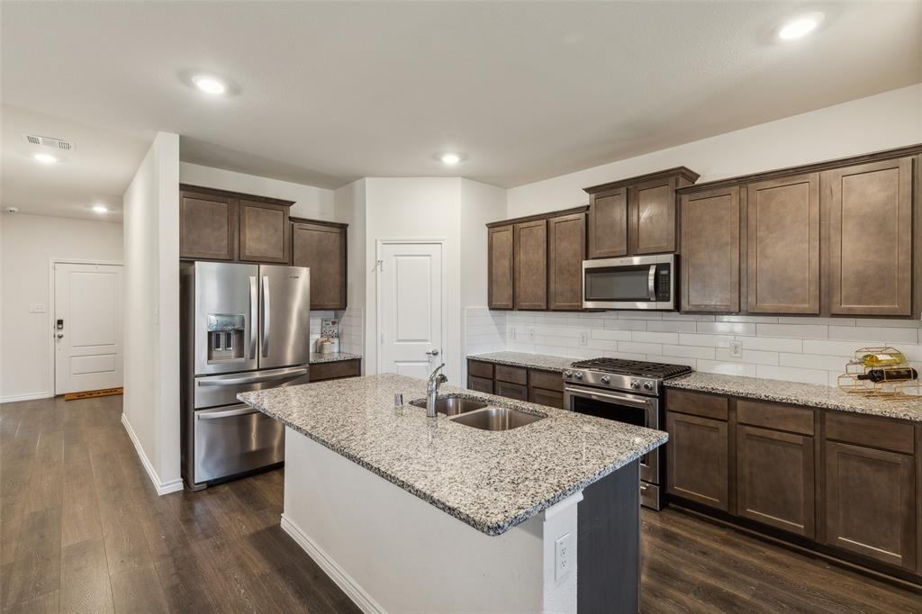 a kitchen with stainless steel appliances granite countertop a sink stove microwave and refrigerator