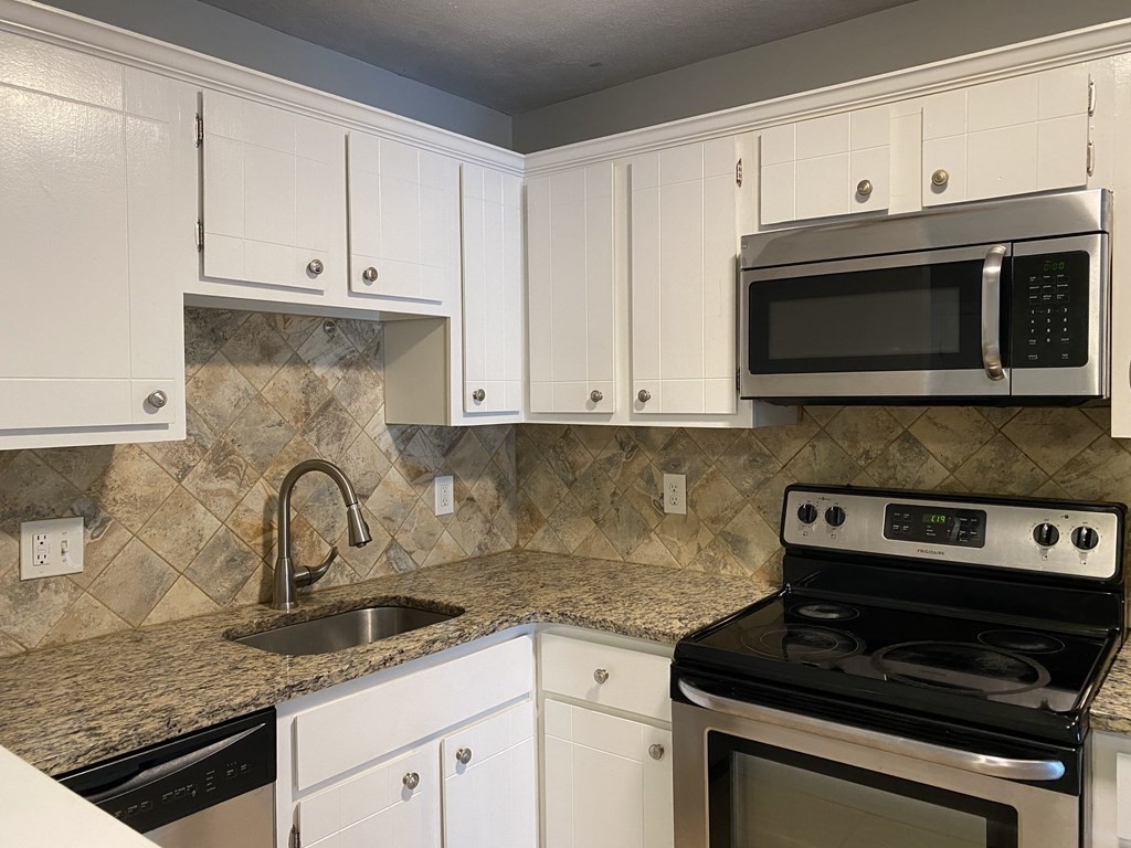 a kitchen with granite countertop white cabinets and stainless steel appliances