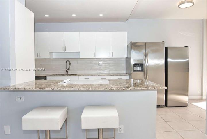 a kitchen with granite countertop a sink a center island stainless steel appliances and cabinets