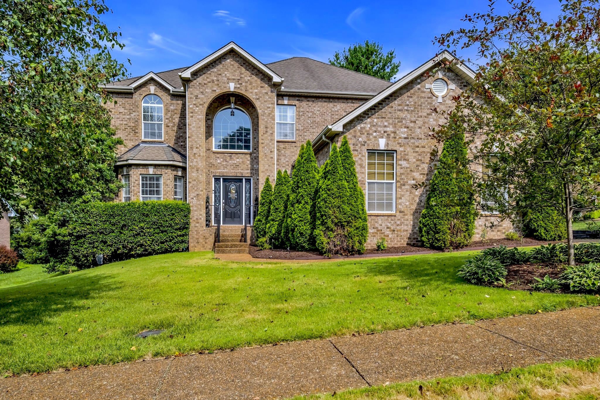 a view of a big house with a big yard and large trees