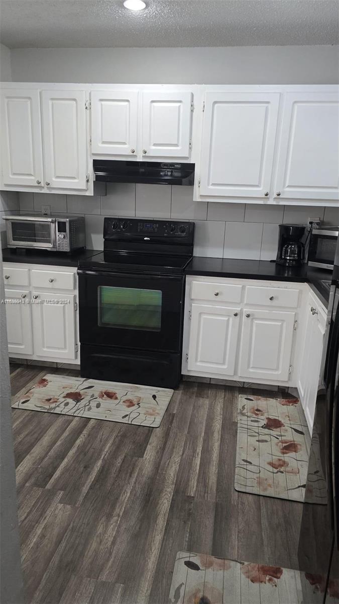 a kitchen with granite countertop a stove a sink and a white cabinets