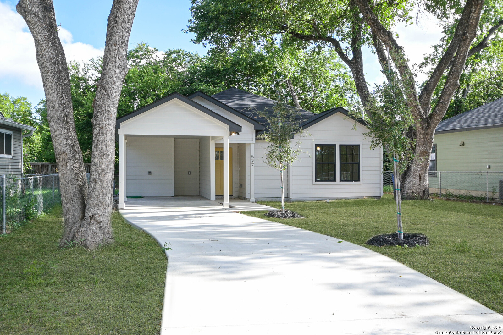 a view of a house with a yard and large trees