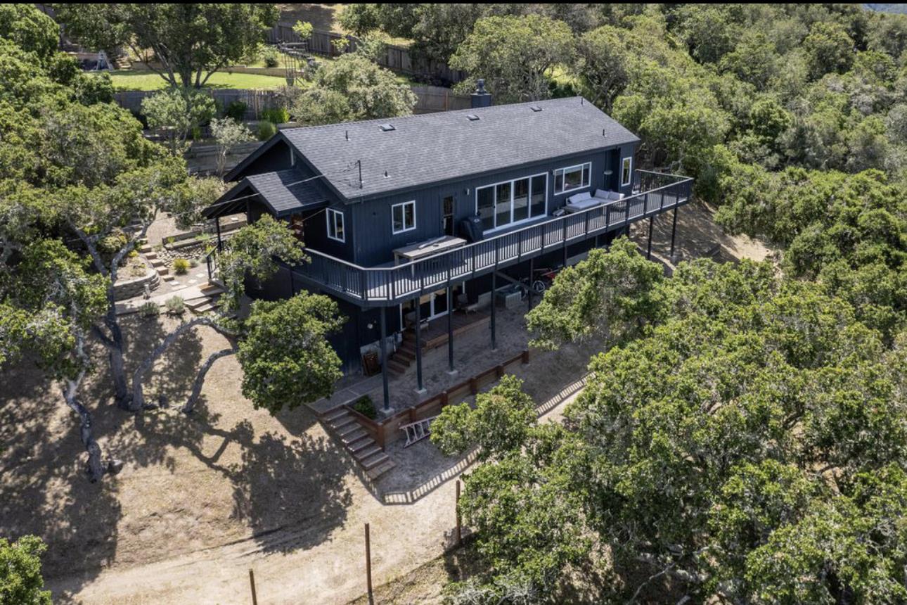 an aerial view of a house with a yard and large trees