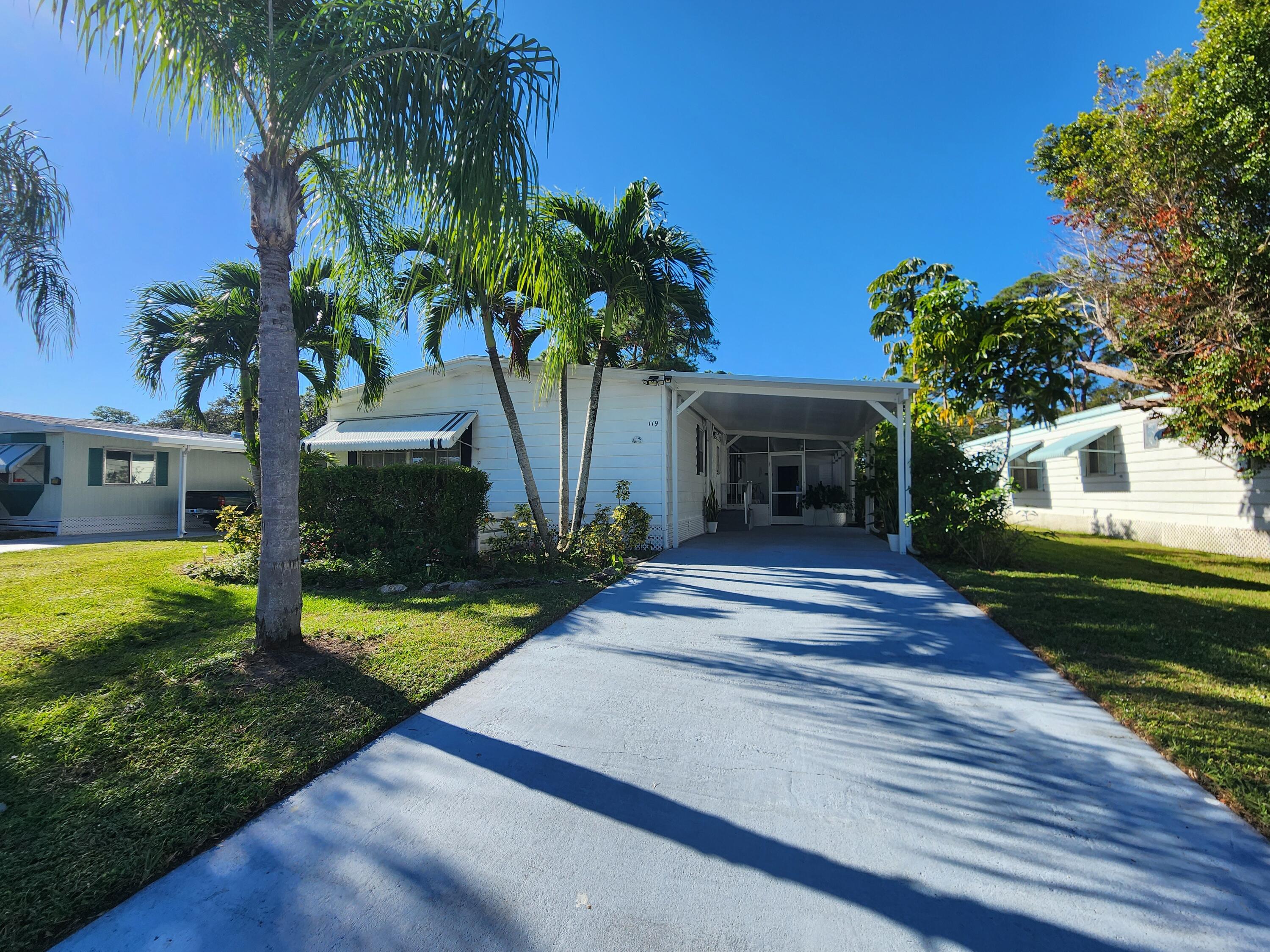 a view of a house with a yard and palm trees