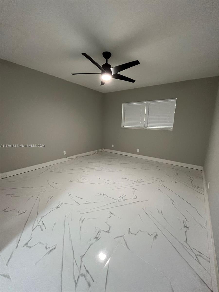 an empty room with a ceiling fan and window