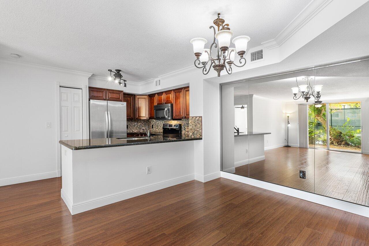 a view of a kitchen with granite countertop a refrigerator a stove and a wooden floor