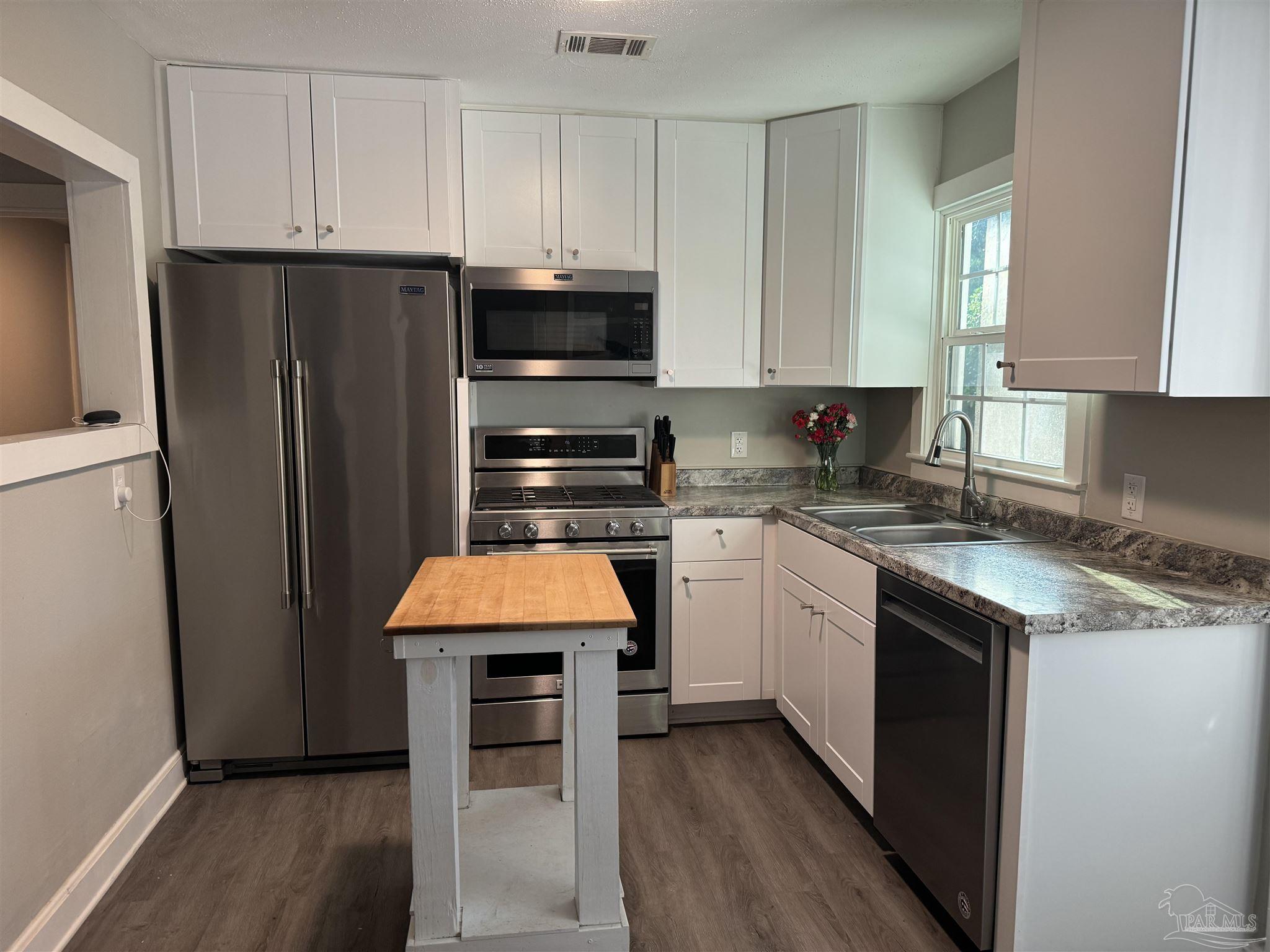 a kitchen with stainless steel appliances granite countertop refrigerator sink and cabinets