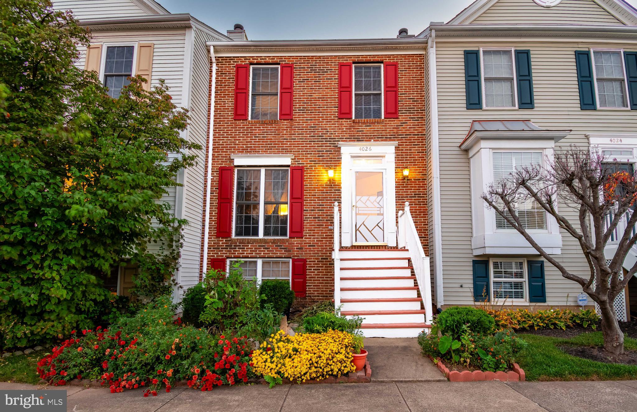 a front view of a house with lots of flowers and trees