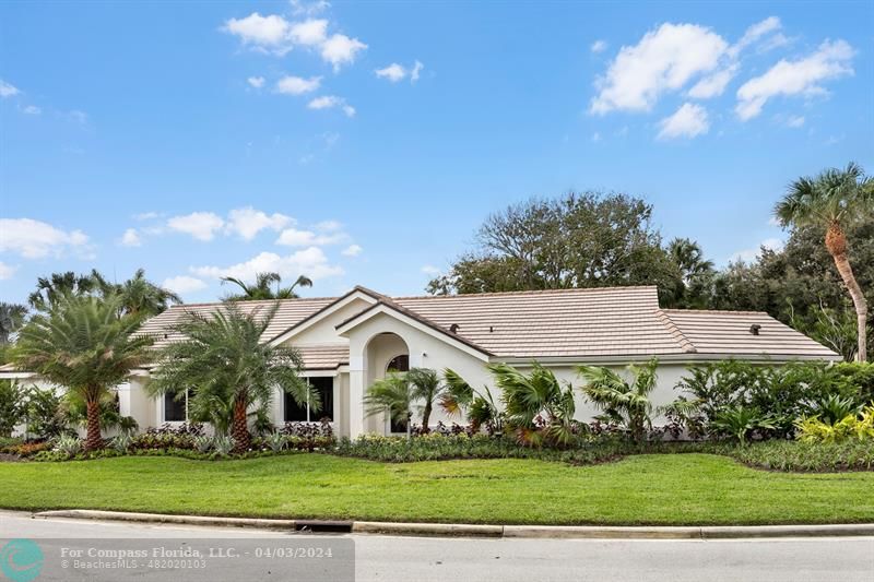 a view of a white house next to a yard with big trees