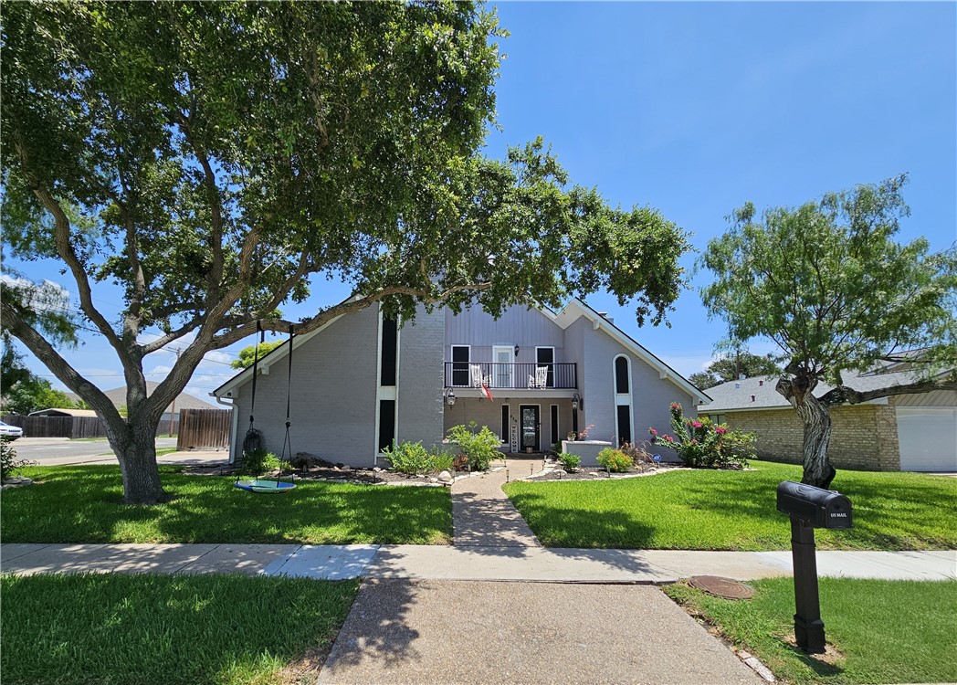 a front view of a house with a yard and large tree