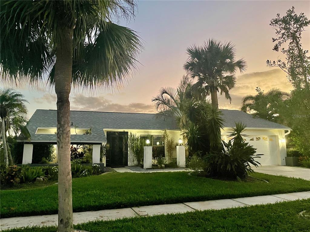 a view of a house with a yard and palm trees