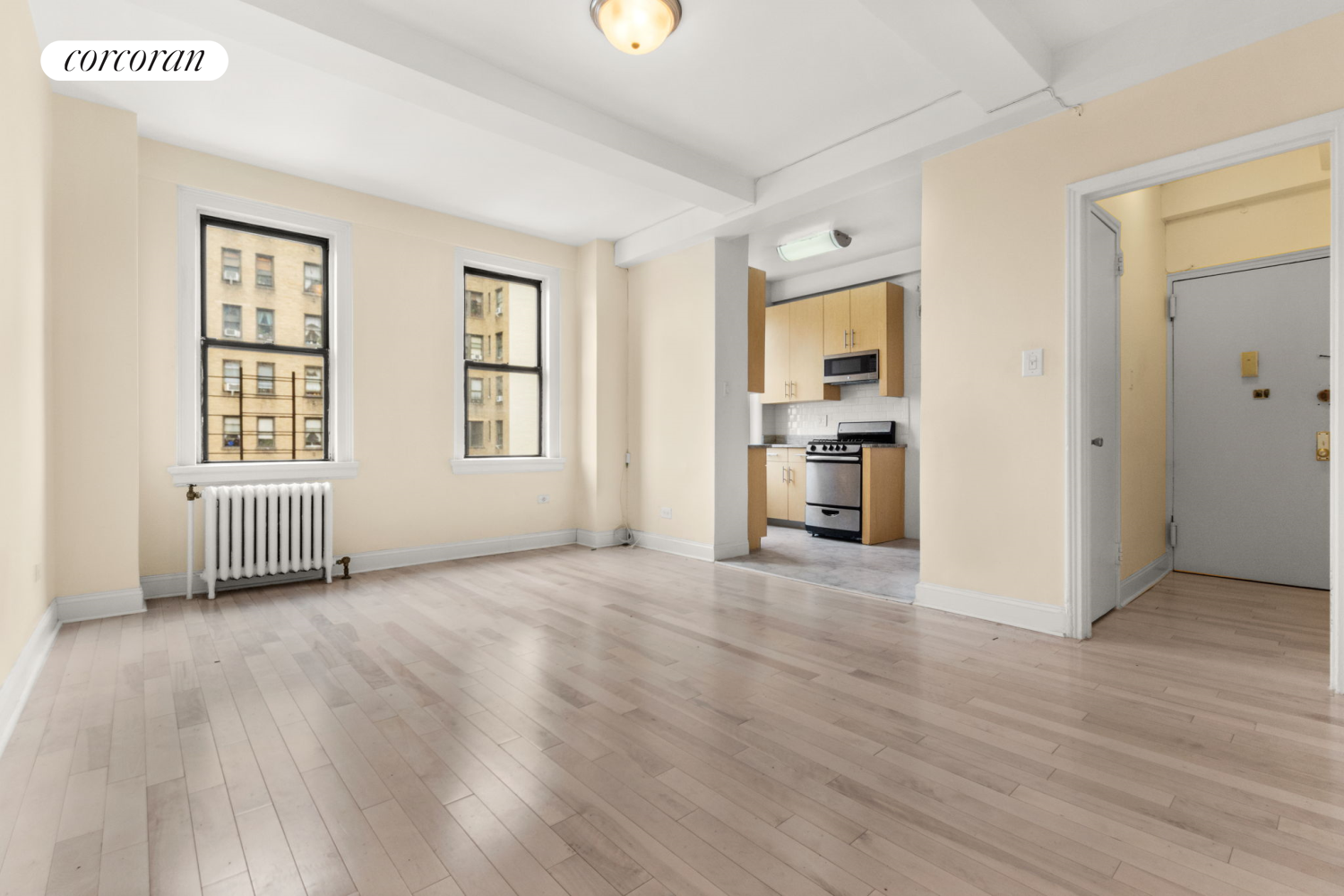 a view of an empty room with a window and wooden floor