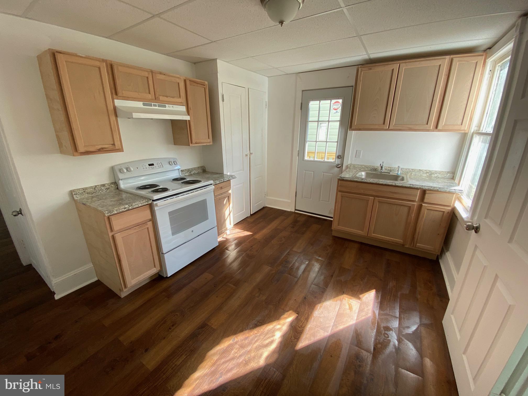 a kitchen with granite countertop wooden floors and white stainless steel appliances