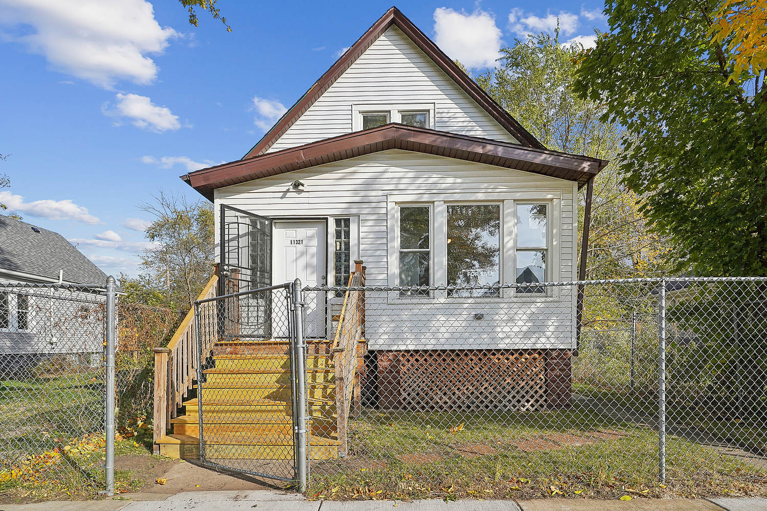 a view of a house with wooden fence next to a yard