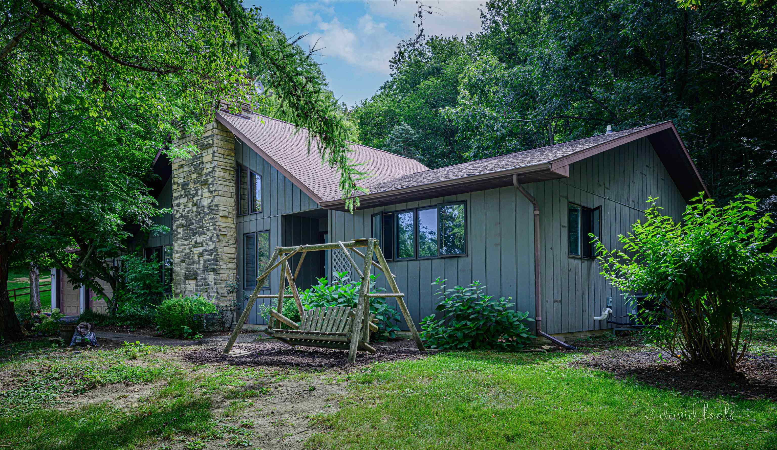 a view of a house with a yard plants and large tree