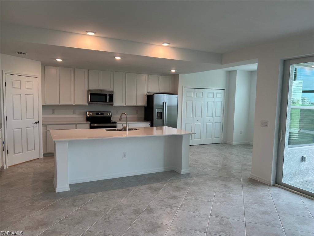 Kitchen featuring white cabinetry, appliances with stainless steel finishes, sink, and an island with sink