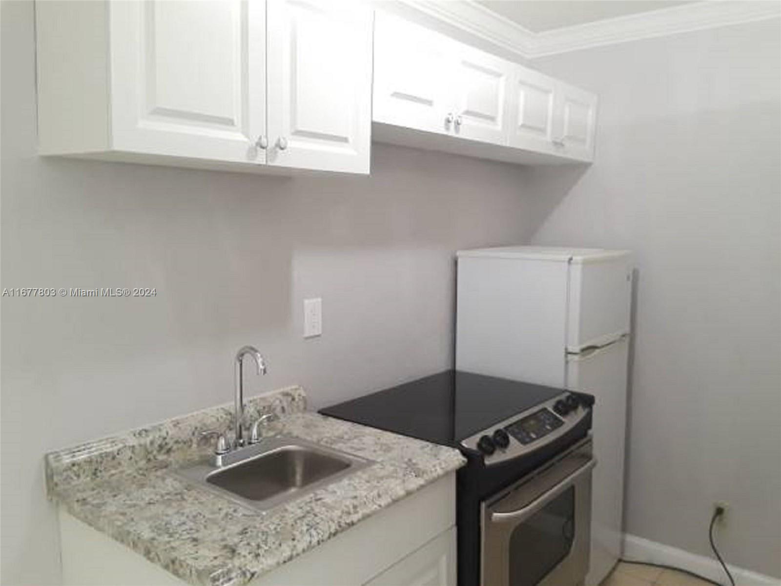 a kitchen with granite countertop a sink stove and cabinets