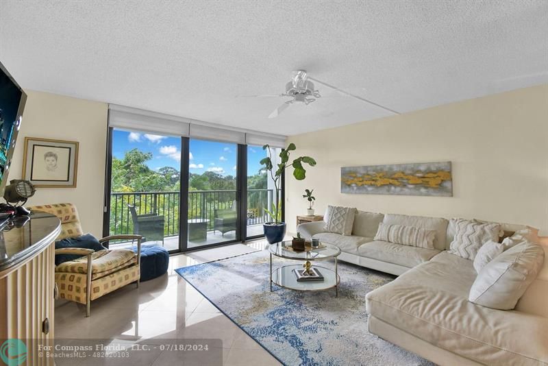 a living room with furniture and a large window with balcony view