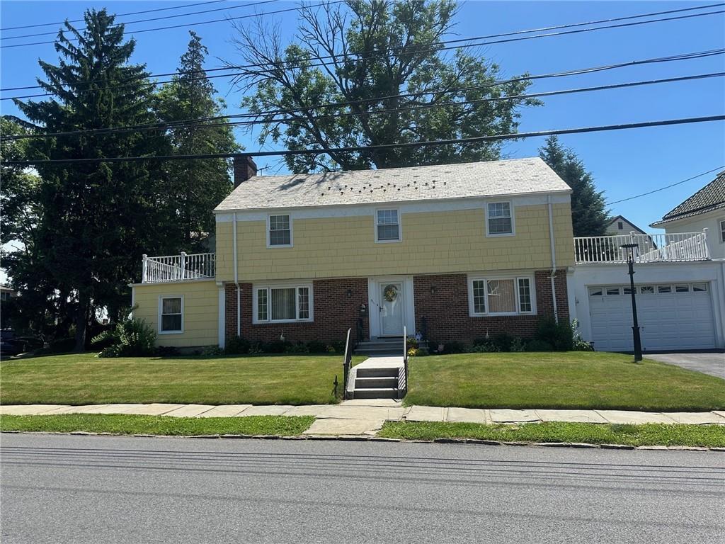 View of front of property with a balcony, a garage, and a front yard