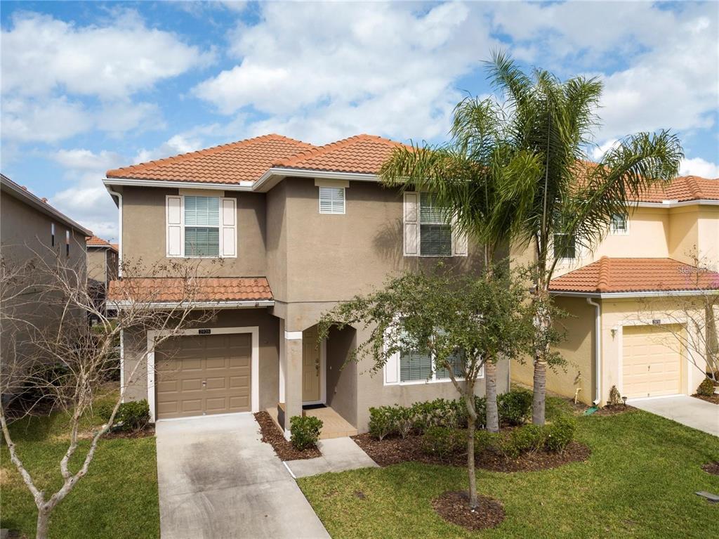 a front view of a house with a yard and palm trees