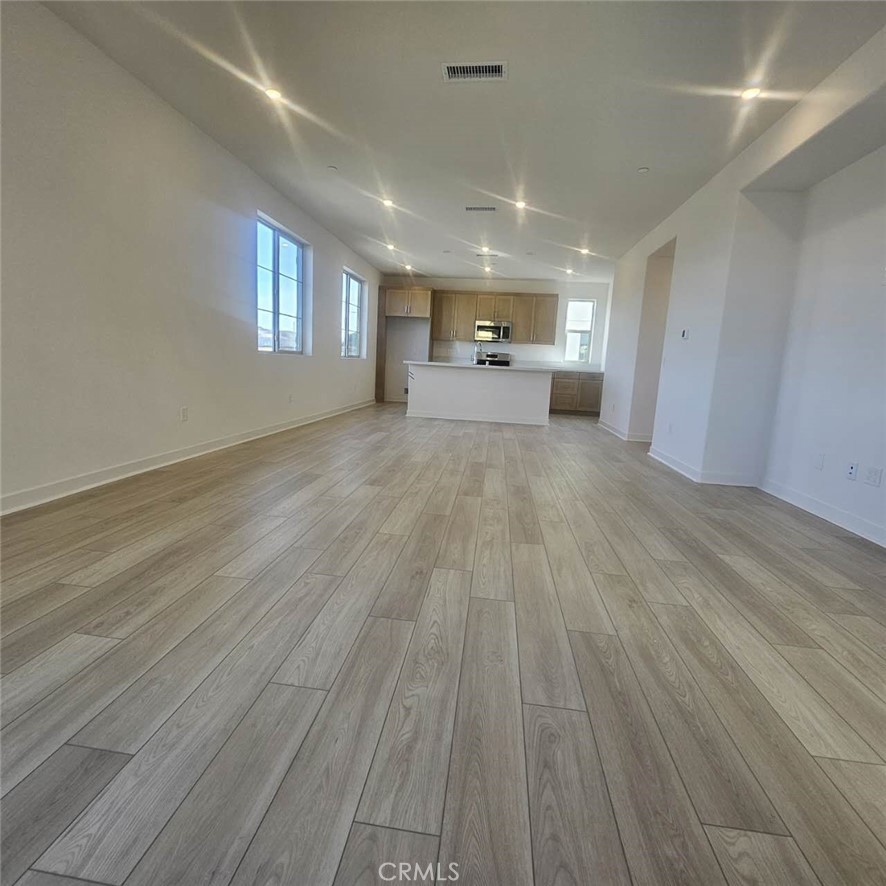 a view of empty room with wooden floor and window