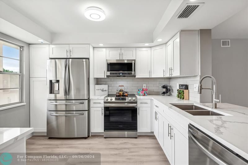 a kitchen with granite countertop white cabinets and stainless steel appliances