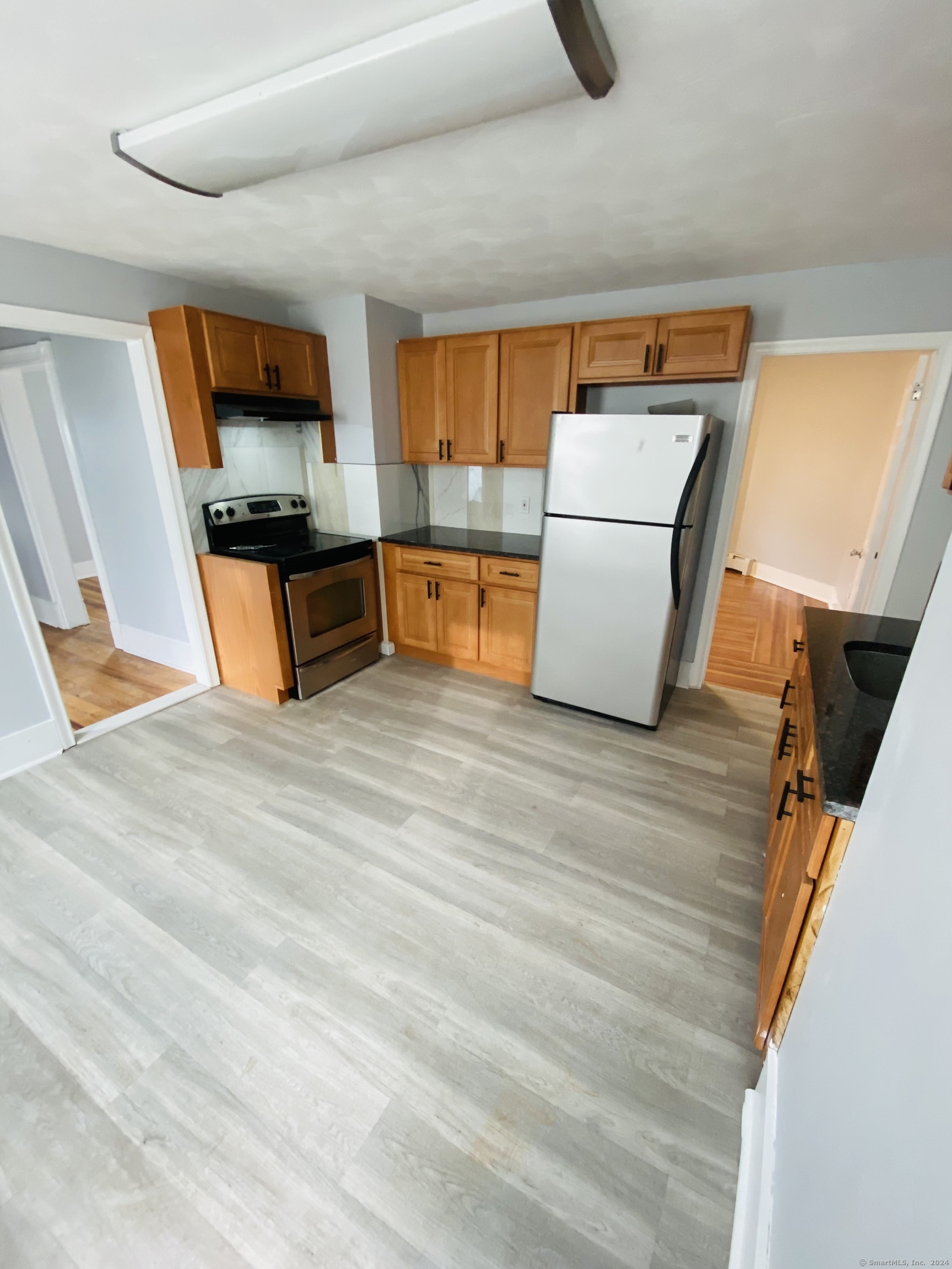 a kitchen with stainless steel appliances wooden floor and a refrigerator